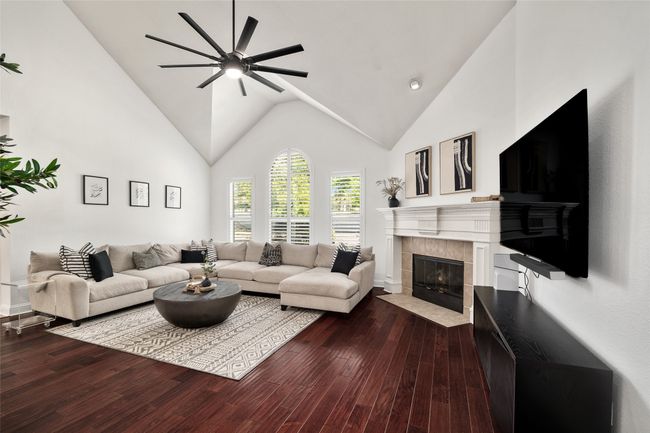 Living room with dark wood-style flooring, high vaulted ceiling, a ceiling fan, and a tiled fireplace | Image 4