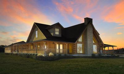 Back house at dusk with covered porch and a yard | Image 2