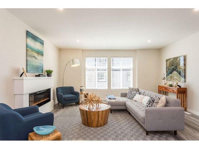 Living area with wood finished floors, baseboards, a glass covered fireplace, and recessed lighting | Image 4
