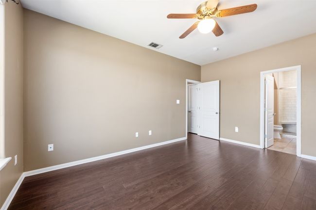Unfurnished primary bedroom downstairs featuring wood flooring, baseboards, and ensuite bathroom | Image 17