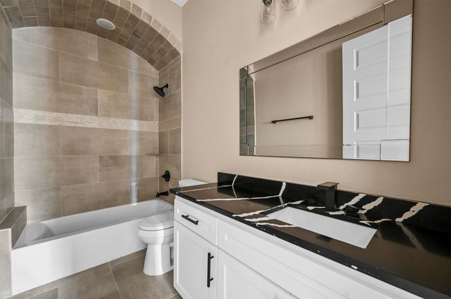 Full bathroom with toilet, tile patterned floors, vanity, and bathing tub / shower combination | Image 22