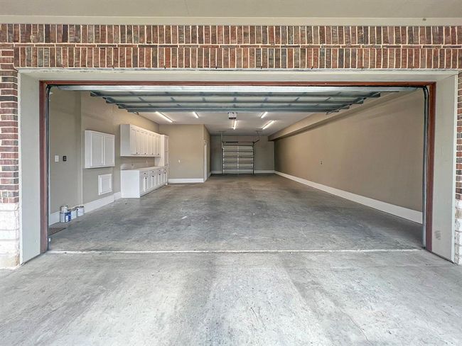 The attached oversized three-car tandem garage is thoughtfully designed with built-in cabinets for ample storage and an under-stairs storage closet for extra space. It includes overhead doors at both the front and rear, providing easy access to the backyard. A private back stairwell leads directly to the upstairs caregiver efficiency apartment, offering both convenience and privacy. | Image 42