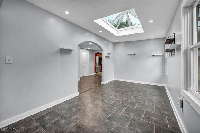 Empty room with arched walkways, a skylight, and recessed lighting | Image 13