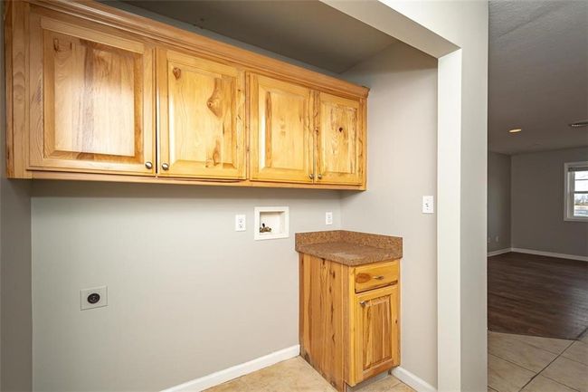 Washroom featuring cabinet space, hookup for a washing machine, hookup for an electric dryer, and baseboards | Image 13