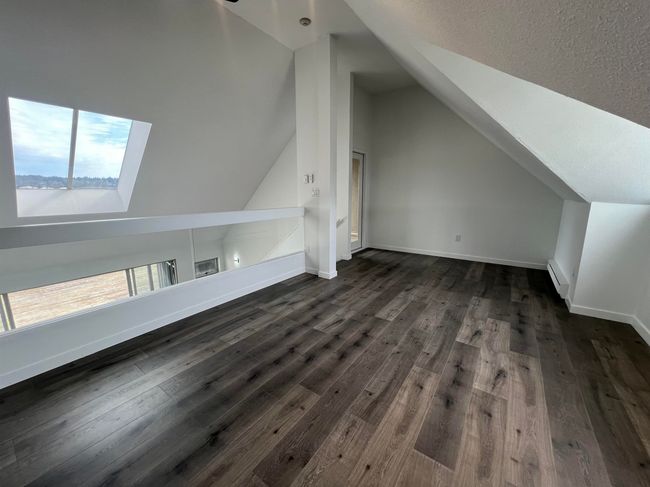 Bonus room featuring vaulted ceiling, baseboard heating, dark wood finished floors, a skylight, and a textured ceiling | Image 21