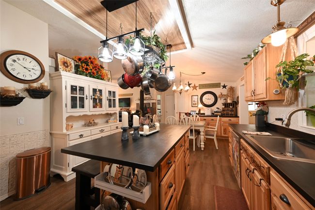Kitchen with dark countertops, a sink, a chandelier, dark wood-style flooring, and glass insert cabinets | Image 22