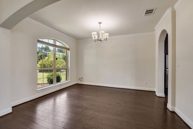 Unfurnished room featuring crown molding, a chandelier, dark wood-style flooring, and arched walkways | Image 8