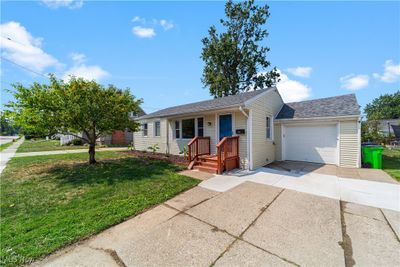 Ranch-style home with a front yard, a garage, and covered porch | Image 1