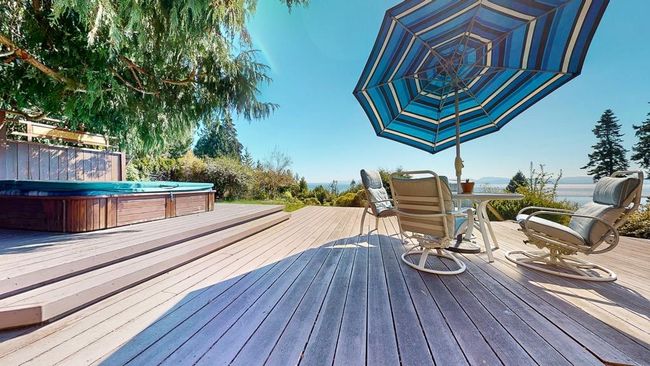 Wooden deck with a covered hot tub and outdoor dining space | Image 9