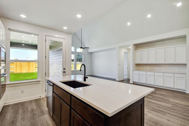 Kitchen featuring white cabinets, light countertops, decorative backsplash, a center island with sink, and lofted​​‌​​​​‌​​‌‌​‌‌​​​‌‌​​‌‌​‌​​​​​‌ ceiling | Image 9