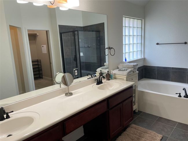 Full bathroom featuring a walk in closet, a stall shower, double vanity, a garden tub, and tile patterned floors | Image 17