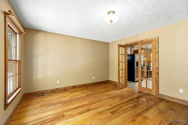 Unfurnished room featuring light wood-type flooring, a textured ceiling, and french doors | Image 29