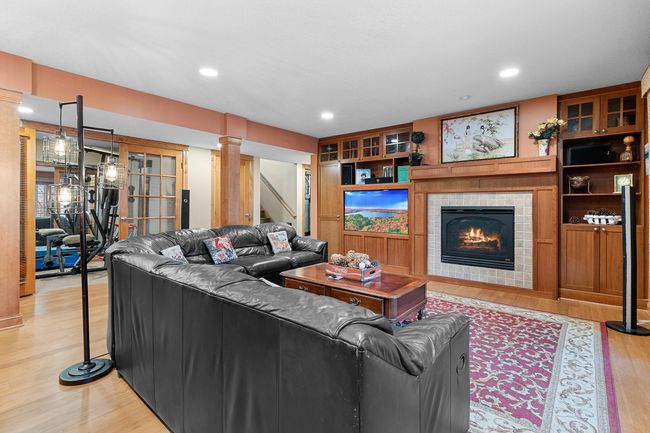 Lower-level recreation room with fireplace, cherry media cabinets. Ceiling speakers connect to media cabinet. | Image 43