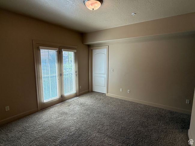 Empty room with carpet floors, a textured ceiling, and baseboards | Image 11