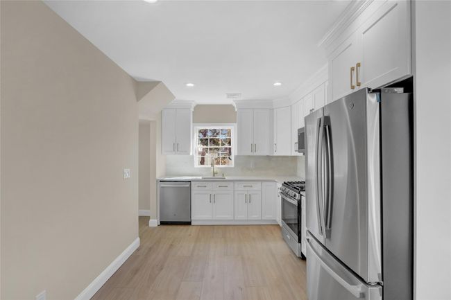 Kitchen with stainless steel appliances, baseboards, white cabinets, light countertops, and tasteful backsplash | Image 7