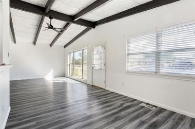 Unfurnished living room featuring dark wood-type flooring, ceiling fan, and lofted ceiling with beams | Image 3