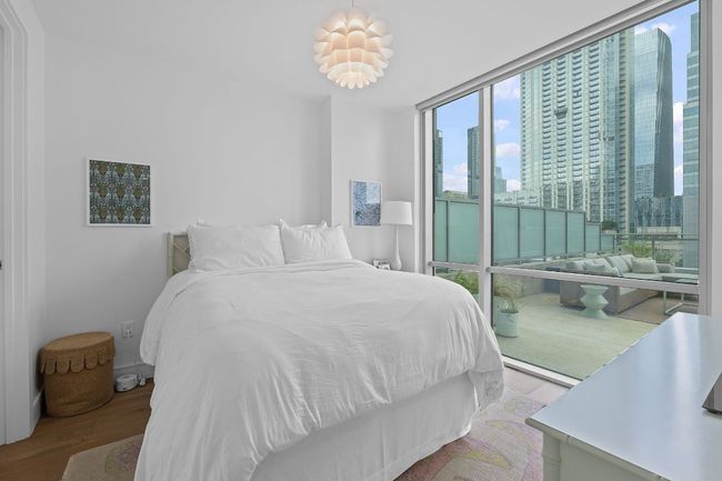 Bedroom featuring wood finished floors, a city view, and a wall of windows | Image 14