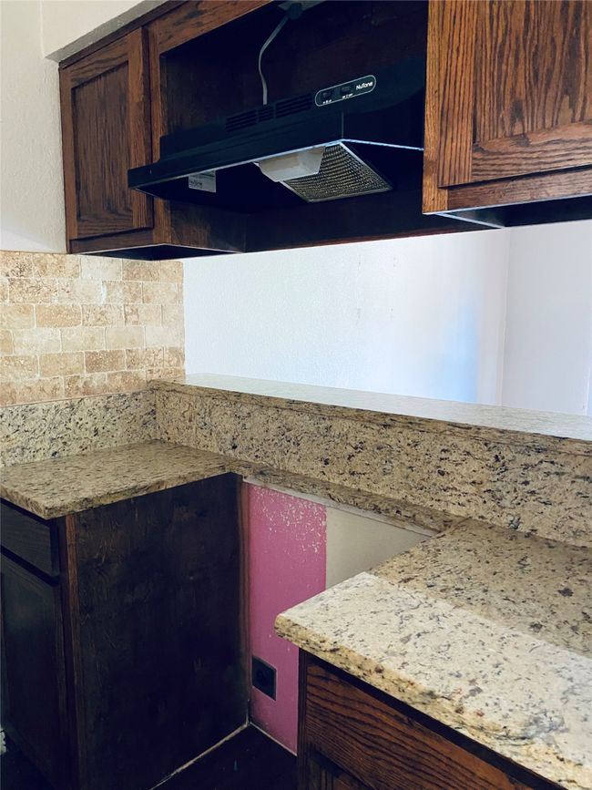 Kitchen with under cabinet range hood, light countertops, backsplash, and dark brown cabinetry | Image 8