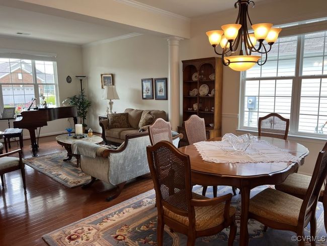 Dining area featuring ornate columns, ornamental molding, a notable chandelier, and dark wood-type flooring | Image 13