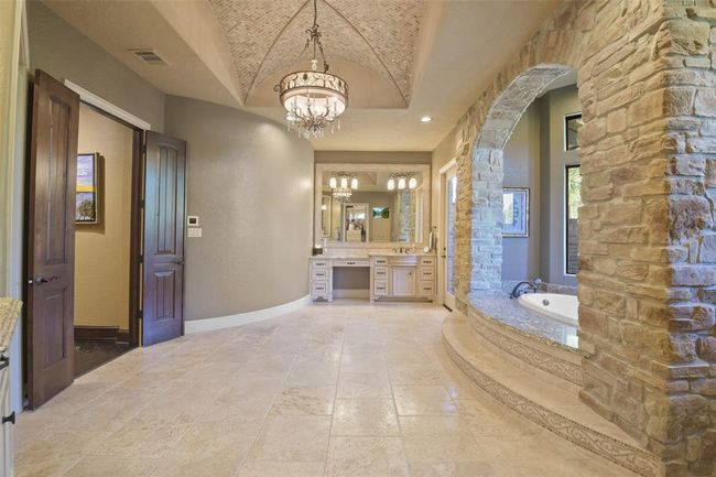 The primary bathroom showcases decorative inlay tiles, his and hers vanities, double-headed steamed shower and 20’x20’ walk-in closet | Image 26