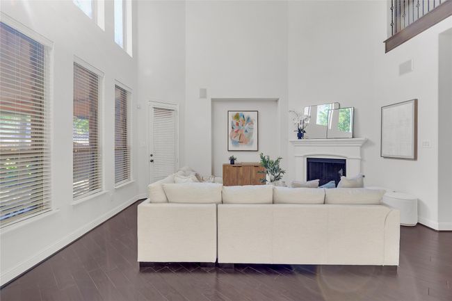 Living area with a towering ceiling, a fireplace, and dark wood-style floors | Image 11