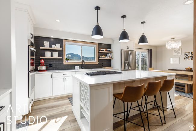 Kitchen featuring open shelves, appliances with stainless steel finishes, a center island, and decorative backsplash | Image 10