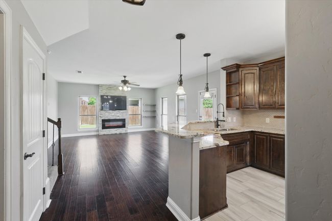 Kitchen featuring a sink, a peninsula, a ceiling fan, open shelves, and plenty of natural light | Image 5