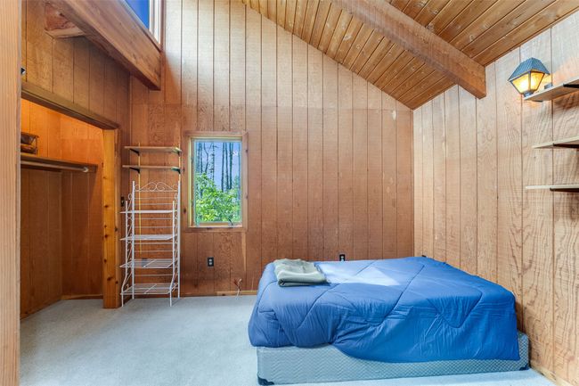 Carpeted bedroom with wood walls, wood ceiling with exposed beams, and high vaulted ceiling | Image 26