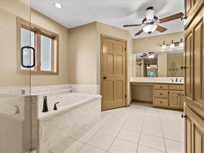 Master bathroom with vanity, a ceiling fan, a bath, tile patterned flooring, and a shower with door | Image 26