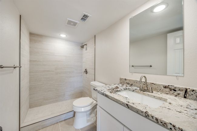 Bathroom with tile patterned floors, vanity, a tile shower, and toilet | Image 23