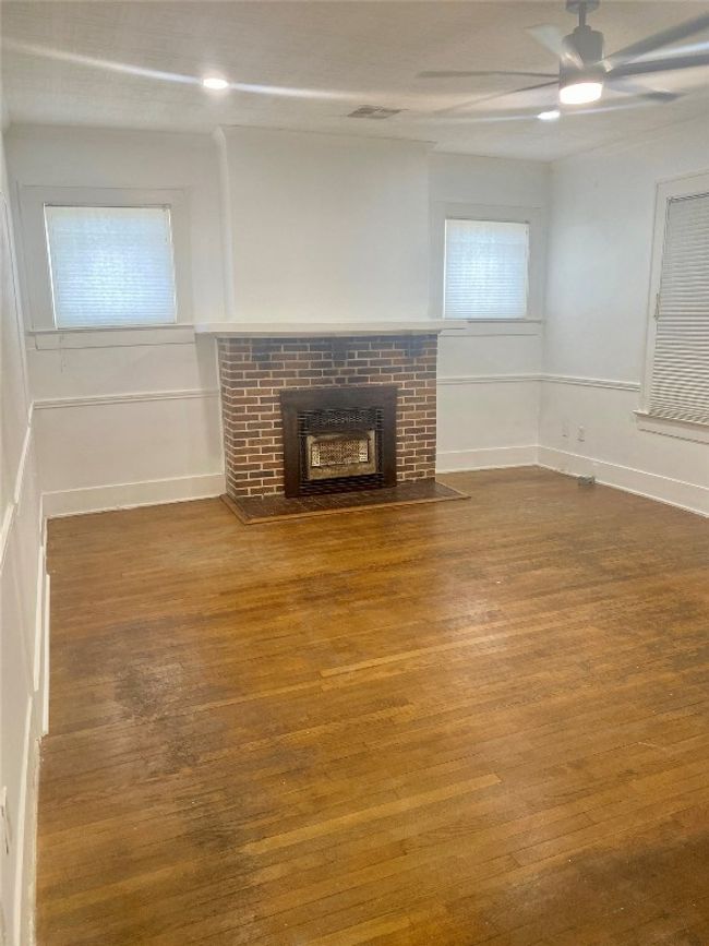 Unfurnished living room with wood finished floors, ceiling fan, and a brick fireplace | Image 4
