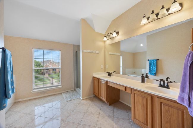 Full bath featuring vaulted ceiling, double vanity, baseboards, tile patterned flooring, and a shower with door | Image 28