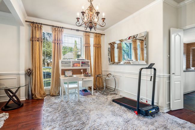 Office area featuring wood finished floors, a decorative wall, ornamental molding, and an inviting chandelier | Image 17