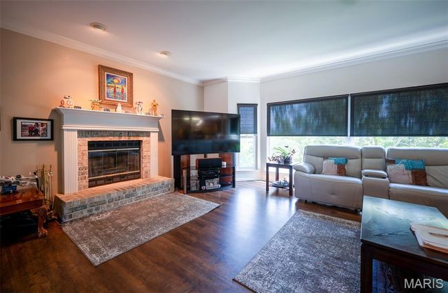 Living area with wood finished floors, ornamental molding, and a brick fireplace | Image 14