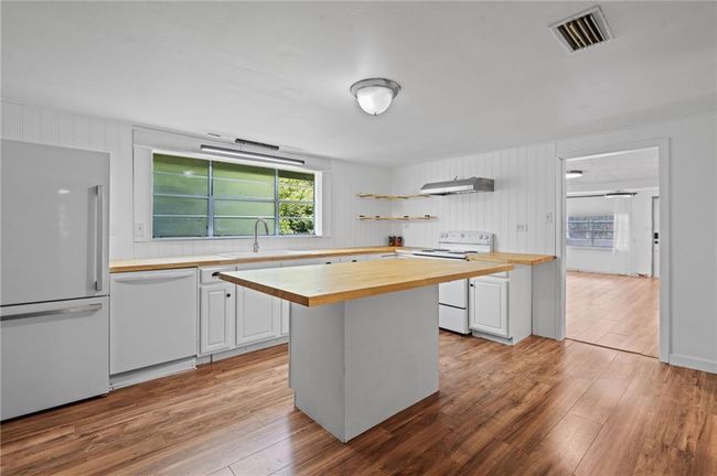 Kitchen featuring wooden counters, white appliances, under cabinet range hood, light wood-style flooring, and open shelves | Image 9