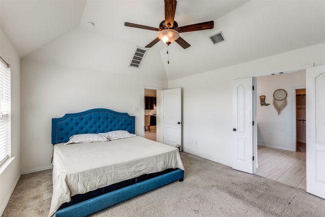 Bedroom featuring lofted ceiling, multiple windows, carpet, and a ceiling fan with bluetooth controlled light | Image 13