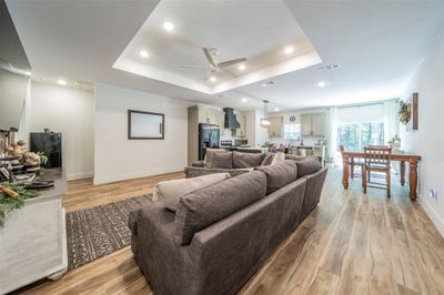 Living room featuring ceiling fan, light hardwood / wood-style flooring, and a raised ceiling | Image 2