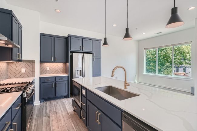 The beautiful kitchen features a spacious quartz island, perfect for barstools, complemented by elegant navy blue cabinets. | Image 22
