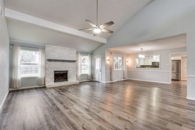 Unfurnished living room featuring a fireplace, hardwood / wood-style flooring, high vaulted ceiling, ceiling fan, and beam ceiling | Image 8
