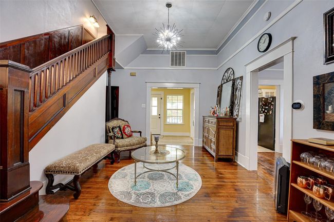 Entrance foyer featuring baseboards, visible vents, an inviting chandelier, stairway, and hardwood / wood-style flooring | Image 4