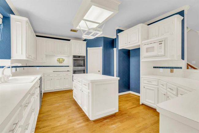 Kitchen features double ovens and an island with pot rack above. | Image 9