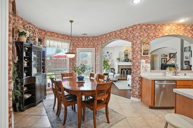 Dining area featuring wallpapered walls, arched walkways, light tile patterned floors, and a tile fireplace | Image 14