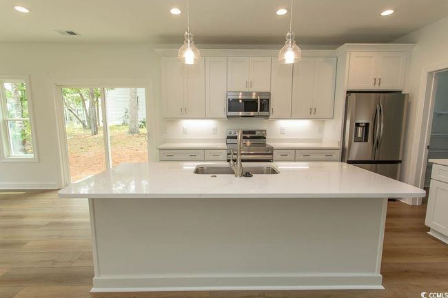 Kitchen featuring stainless steel appliances, recessed lighting, light wood finished floors, white cabinetry, and an island with sink | Image 5