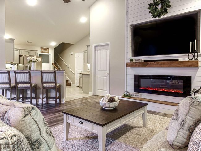 Living room with a fireplace, light wood-type flooring, high vaulted ceiling, and ceiling fan | Image 6