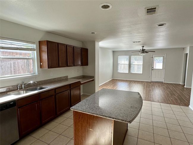 Kitchen with visible vents, a center island, a sink, stainless steel dishwasher, and light tile patterned floors | Image 4