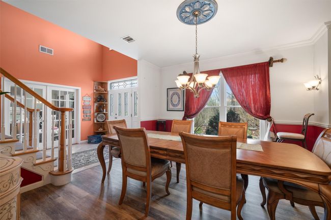 Dining area with ornamental molding, a notable chandelier, wood finished floors, and visible vents | Image 4