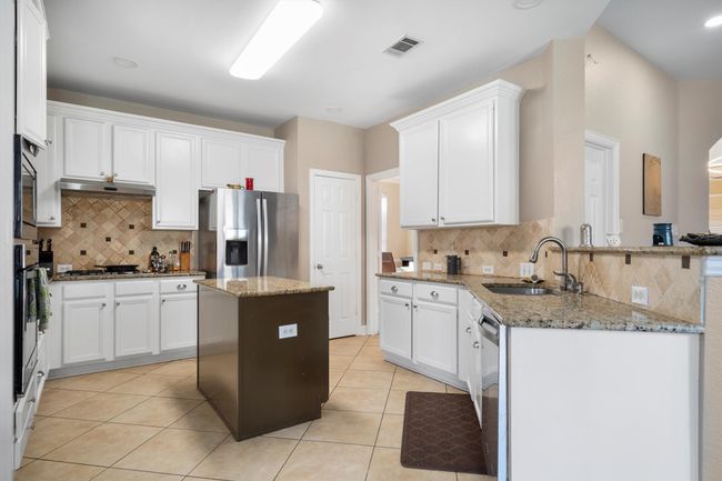 Kitchen with appliances with stainless steel finishes, a peninsula, decorative backsplash, light tile patterned floors, and recessed lighting | Image 15