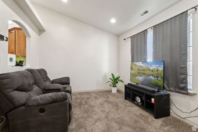 Carpeted living room featuring lofted ceiling, arched walkways, baseboards, and recessed lighting | Image 11