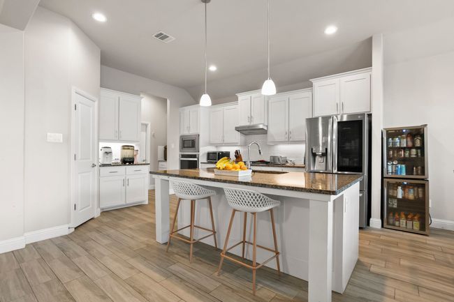 Kitchen with a kitchen breakfast bar, white cabinetry, an island with sink, appliances with stainless steel finishes, and recessed lighting | Image 9