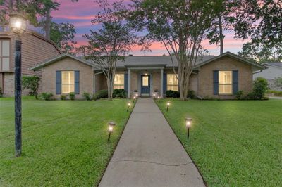 Discover your dream home: a charming single-story residence nestled in a serene neighborhood, boasting a beautifully manicured lawn and inviting pathway that leads to a warm, welcoming entrance, all set against a stunning sunset backdrop. | Image 2